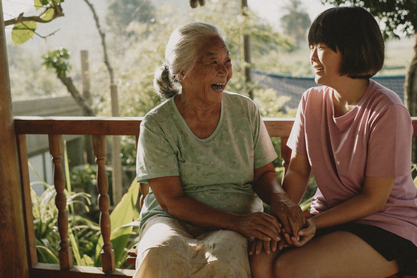 Grandmother and her daughter sharing a laugh on a teak veranda
